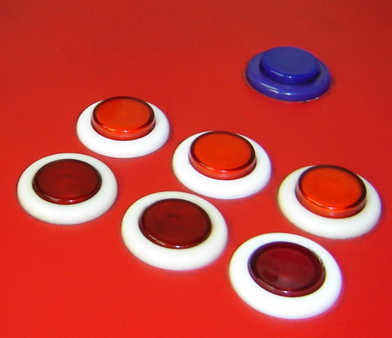 A row of round arcade buttons in red and blue, evoking the arcade hall where price tracking began